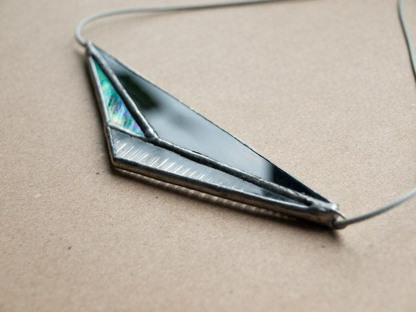 Close-up of a pendant made of black and clear glass on a background of kraft paper.