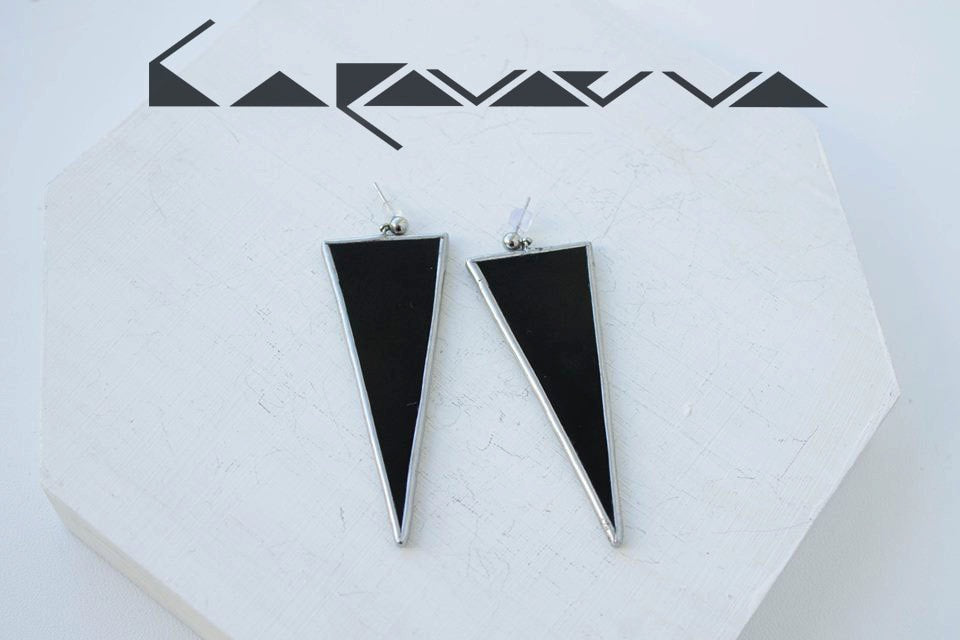 Black stained glass triangle earrings on white background flat lay.