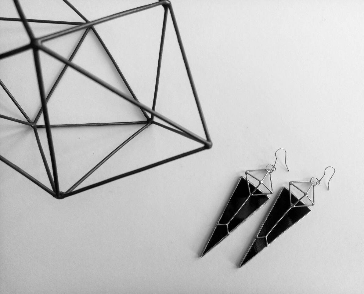 Geometric black earrings next to metal decor in minimalist style
