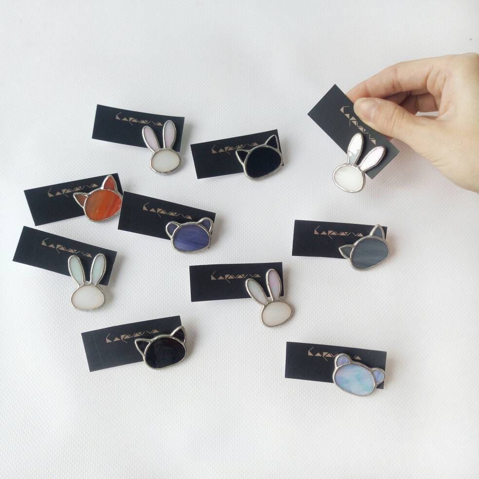 The photo shows cute stained glass brooches in the shape of a bear, a cat, a bunny, and a fox in different colors that you can choose as a gift for a jewelry lover, a student, a friend, or a child.