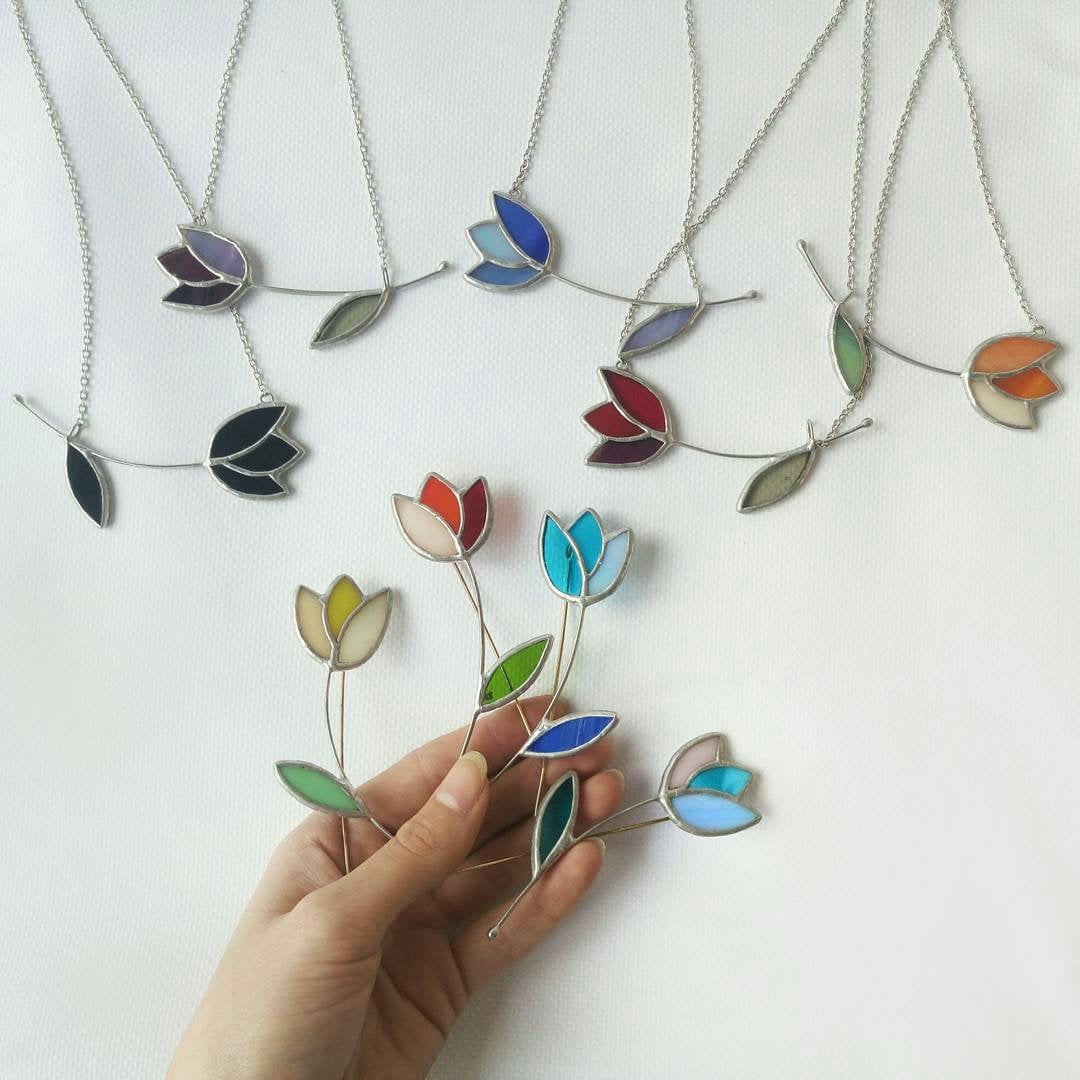 Hand holding colorful stained glass tulip brooches artisan floral pins gift for gardeners