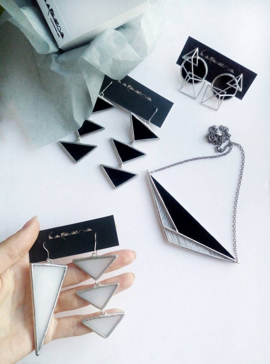 Close-up of a pendant made of black and clear glass on a background of kraft paper.The pendant in a composition with other jewelry - a modern geometric handmade decoration.