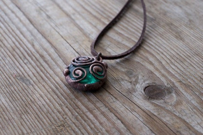 Close-up of copper wire wrapped pendant with deep green glass
