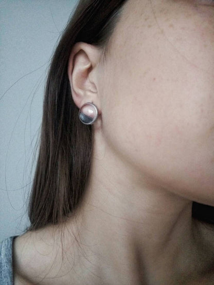 Round white glass earrings worn on ear close-up