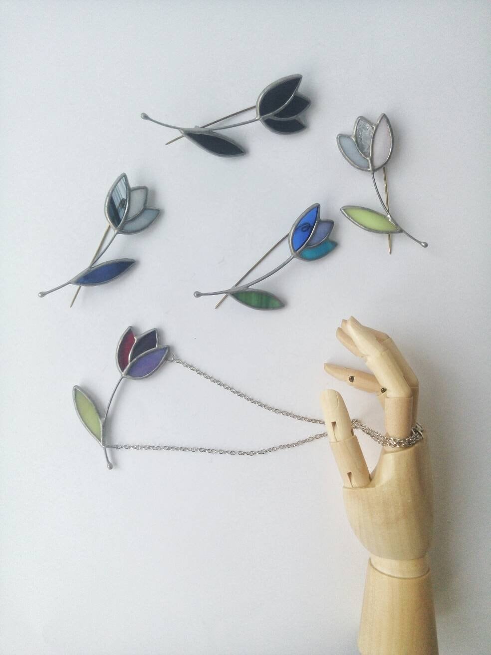 Minimal stained glass flower brooch collection displayed on white background botanical handmade jewelry