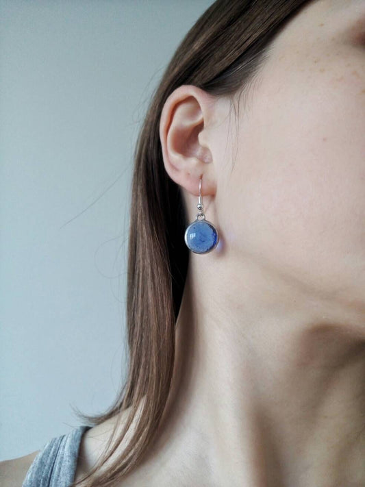 Blue stained glass drop earrings on model