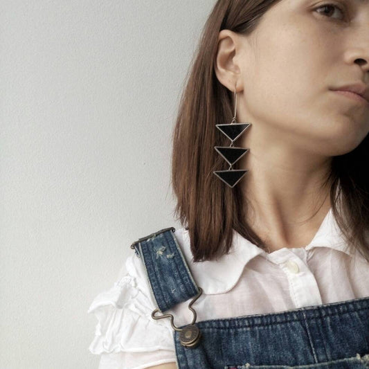 Girl wearing large black triangle stained glass earrings