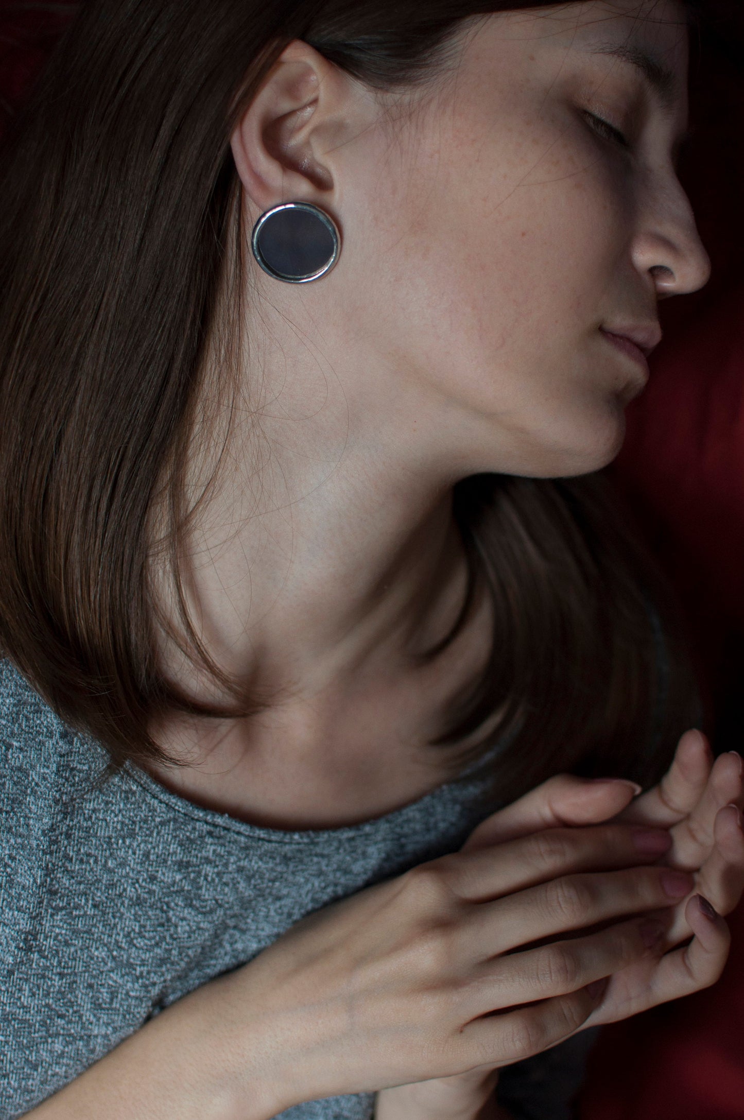 Round mirrored earrings-pendants made of stained glass on a girl's ear