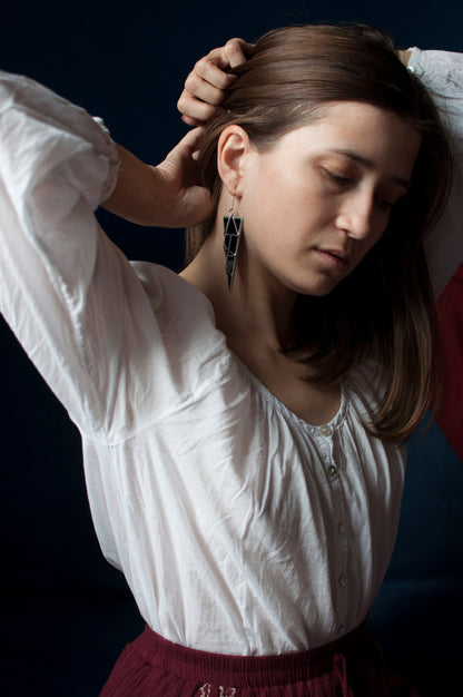 Model wearing long black brutalist triangle earrings with geometric design