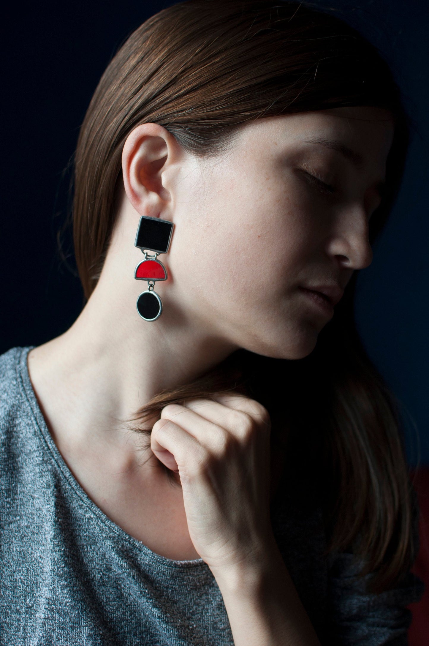 Side view of a model in large black and red geometric earrings.