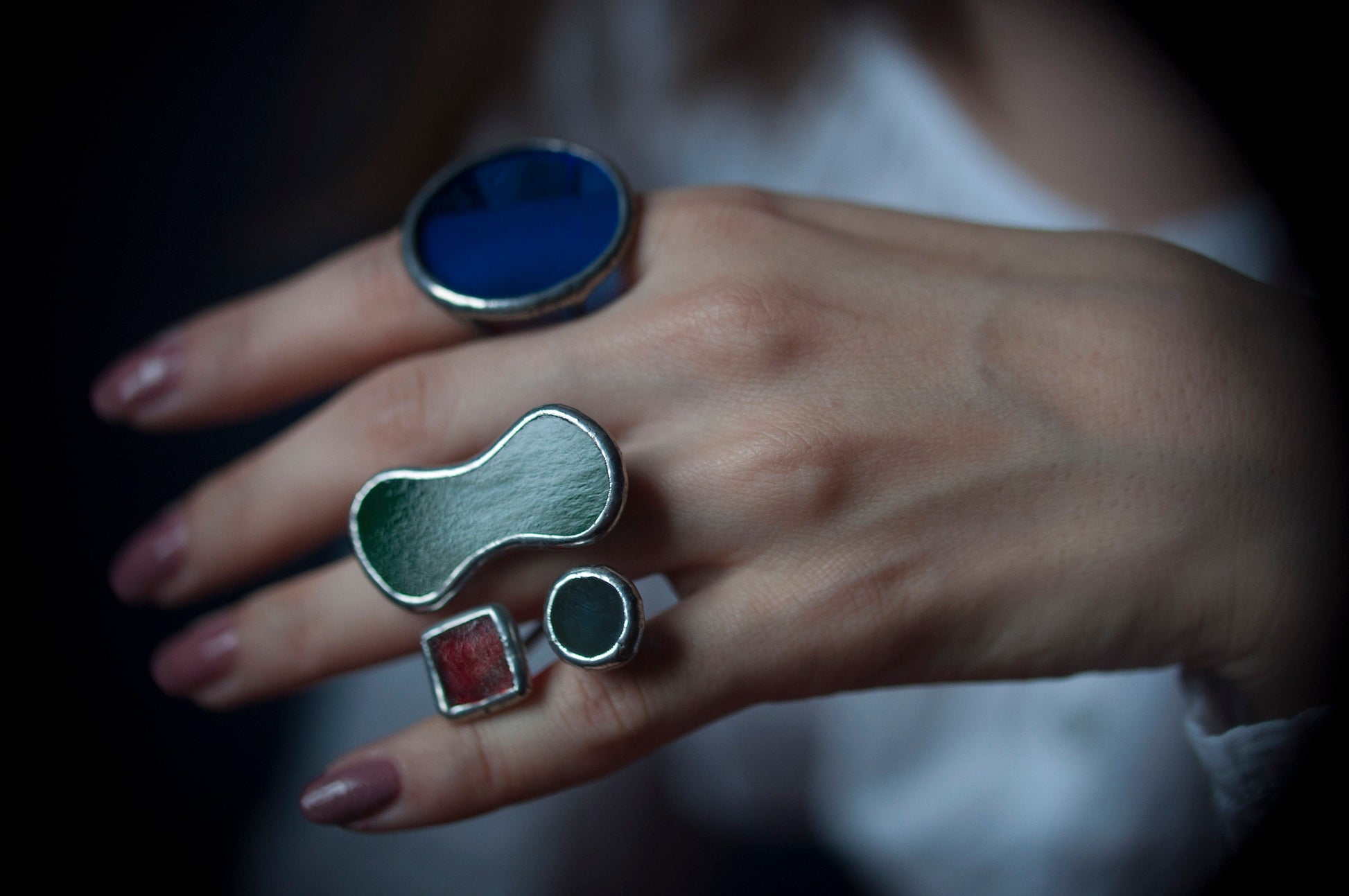 Close-up of handmade geometric ring with colorful stained glass — red, green, and blue shapes in silver setting
