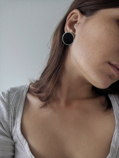 Black round stud earrings worn on ear minimalist enamel disc
