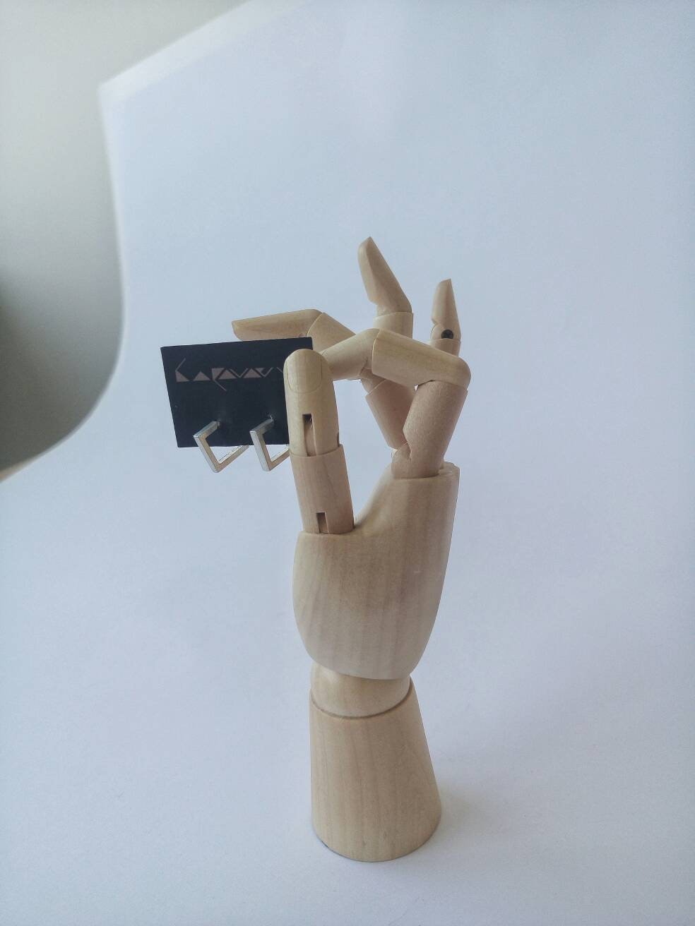 Minimalist square sterling silver earring on white background. May include: Silver hoop earrings with a geometric design. The earrings are displayed on a black card with the word 'Laavaay' printed on it.