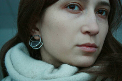 Woman wearing large geometric stained glass earrings with silver posts