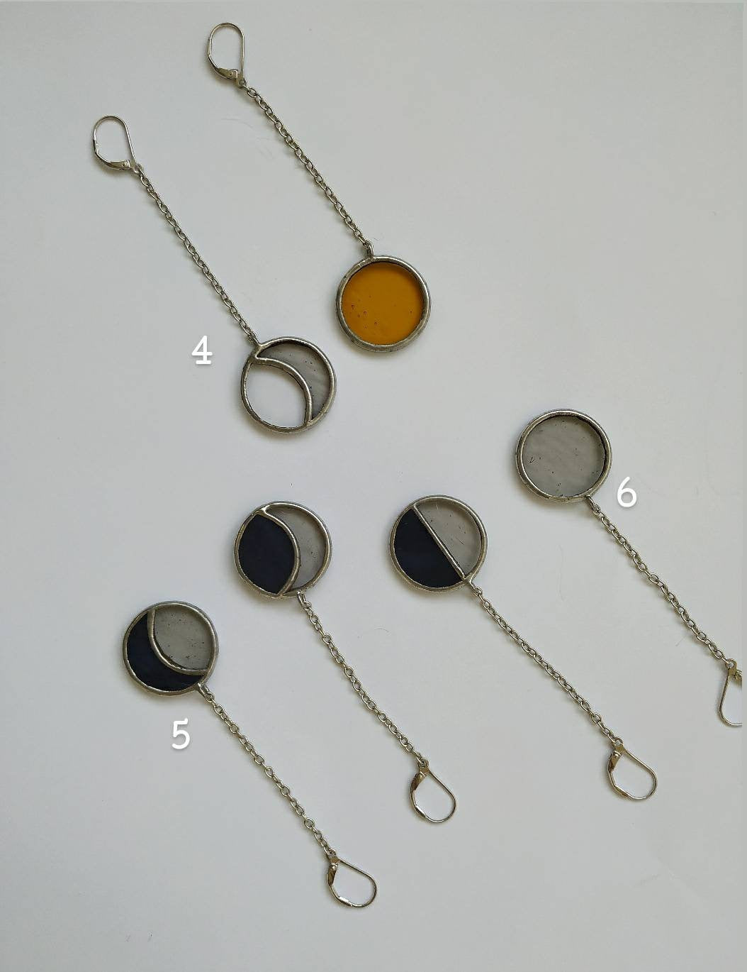 Celestial asymmetric earrings showing moon phase design