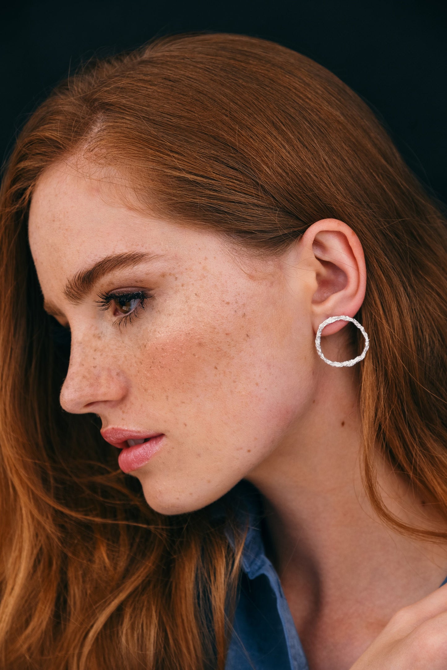 Side profile of model wearing sterling silver hammered hoop earrings