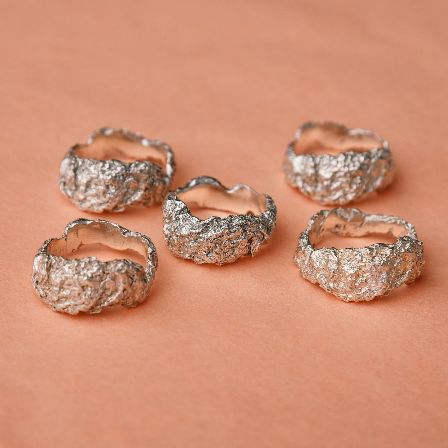 Hammered sterling silver ring with crumpled dome texture on neutral background