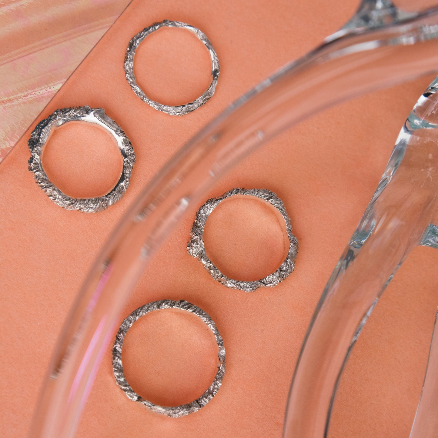 Several silver rings laid out on a table as handmade jewelry.