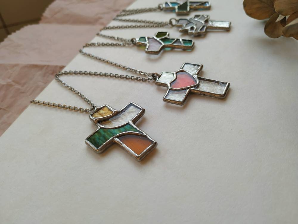 Several stained glass cross pendants displayed on a white surface