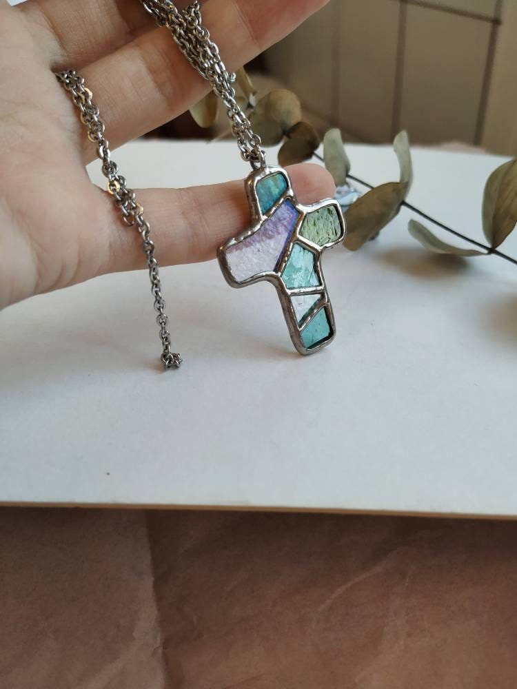Close-up of stained glass cross necklace with purple and blue tones