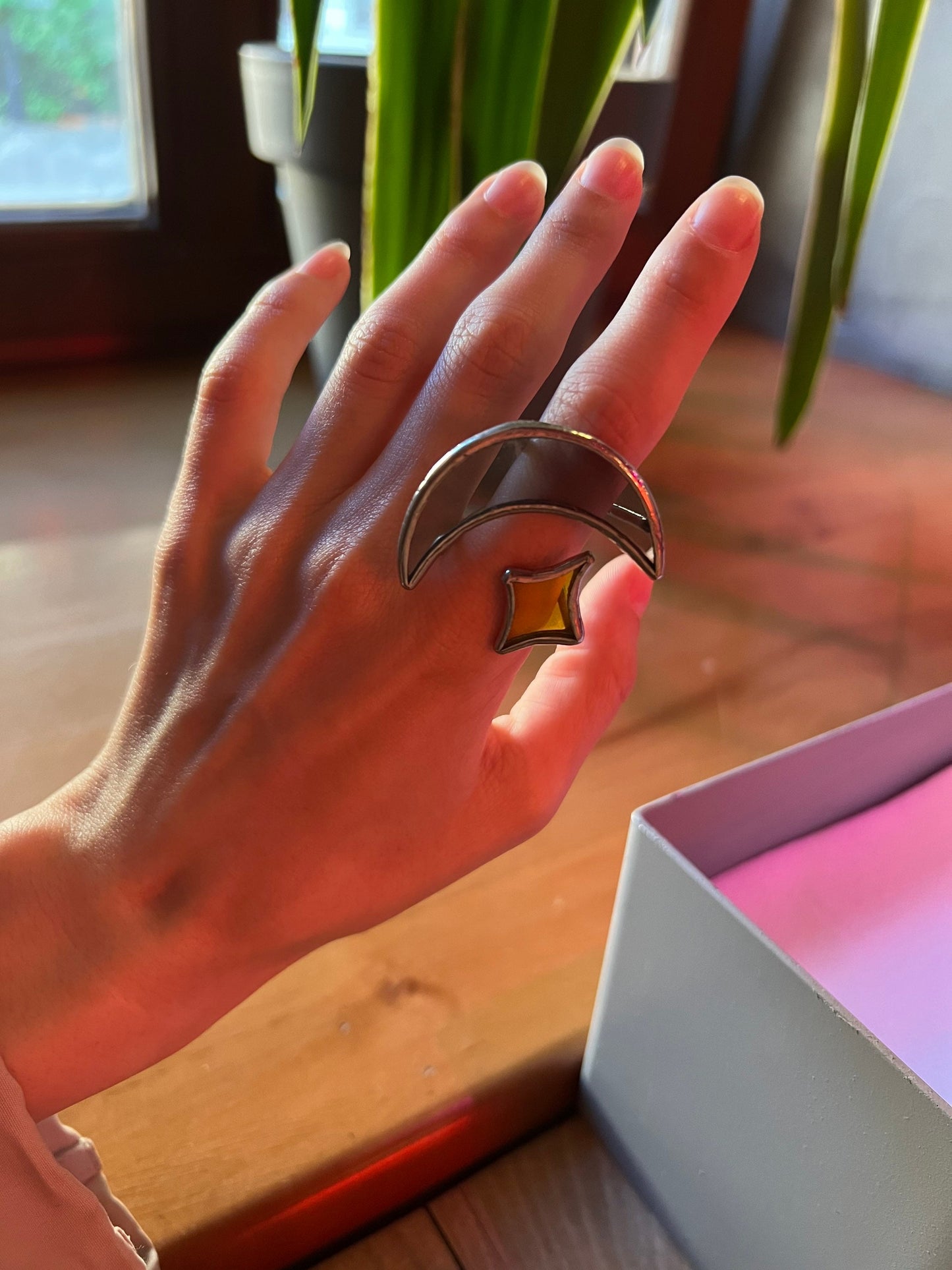 Moon and star statement ring on hand in warm natural light near wooden table