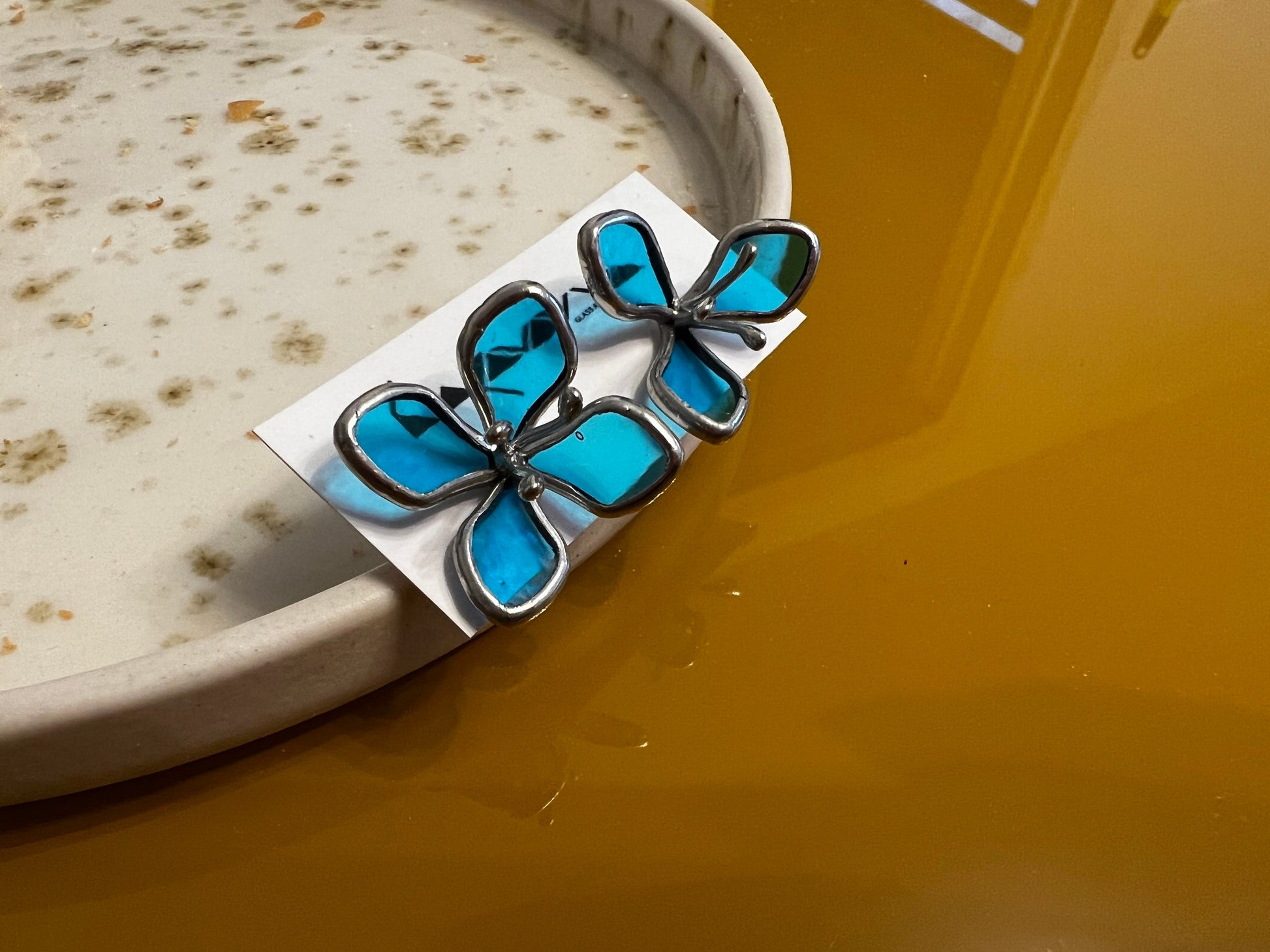 Blue stained glass hydrangea stud earrings on ceramic plate