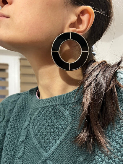 Close-up of big black geometric hoop earrings on model