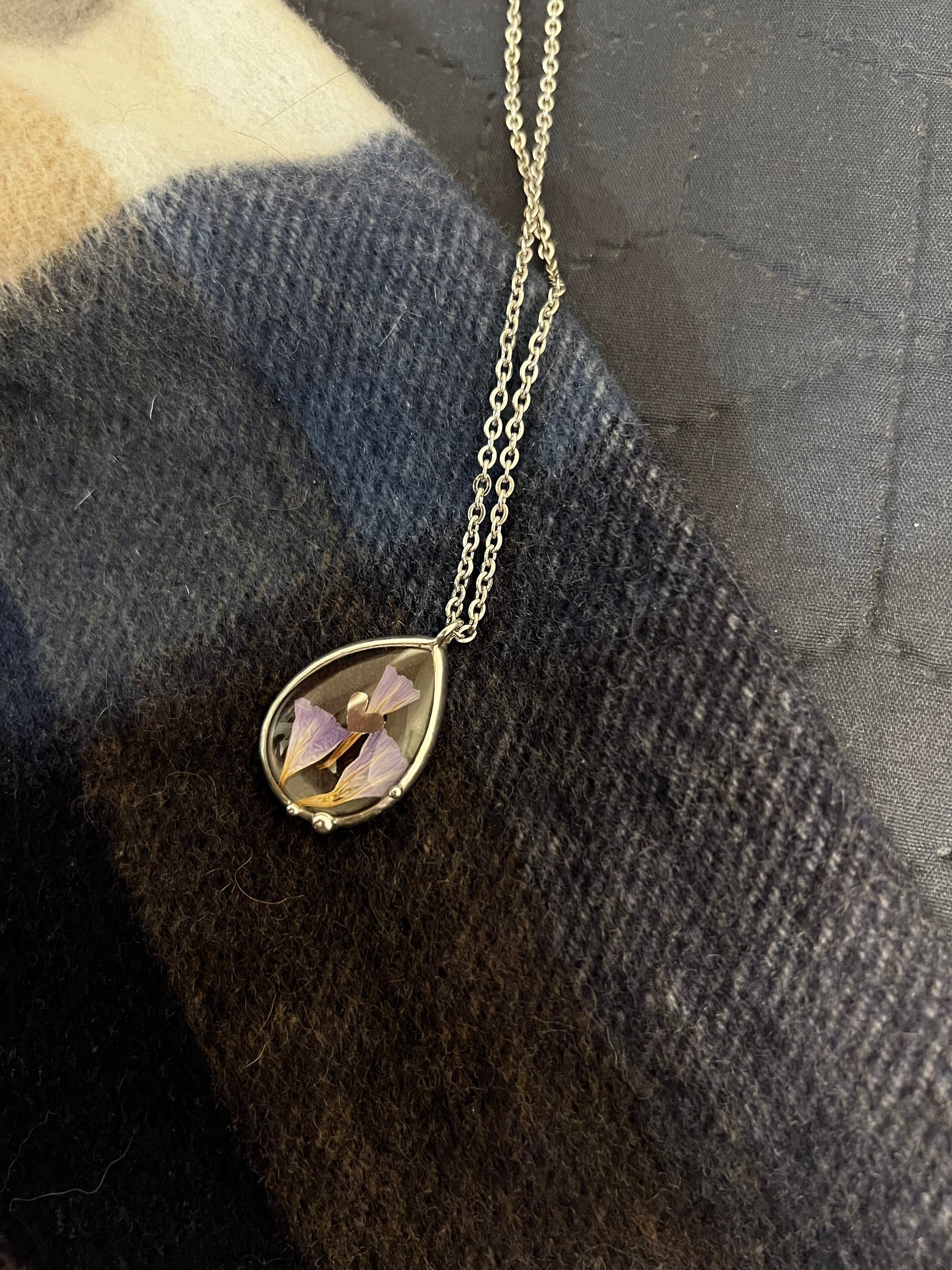 Purple dried flower glass necklace photographed on sweater texture