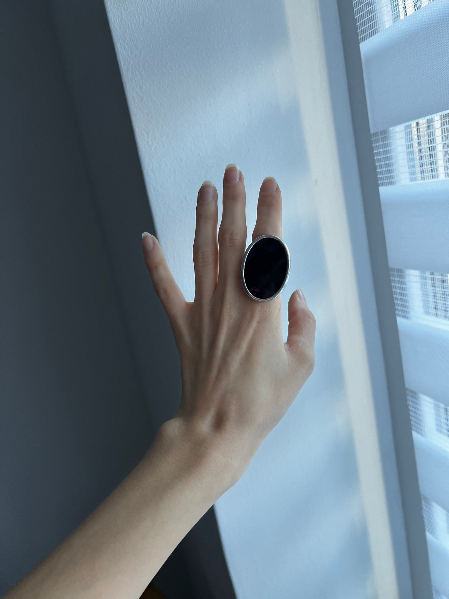 large oval elegant black ring on a woman's hand against a window background