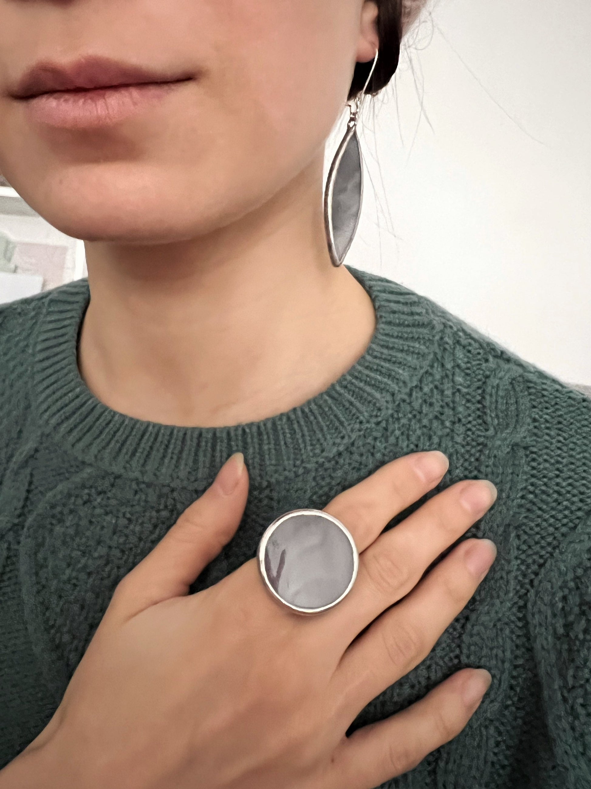 Big round gray glass statement ring on woman’s hand