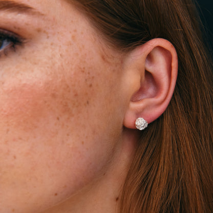 Textured silver earrings displayed on blue background.