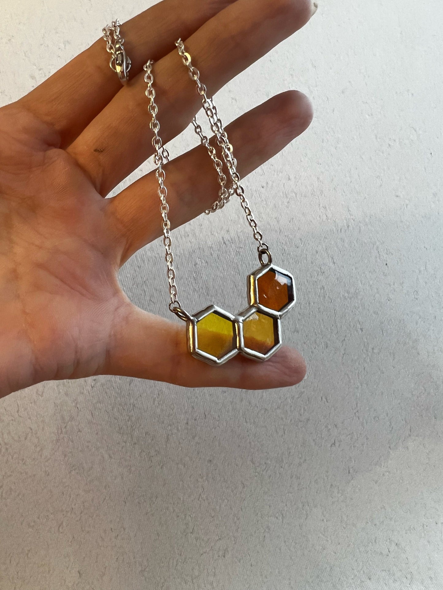 Honeycomb glass necklace shown on palm close up