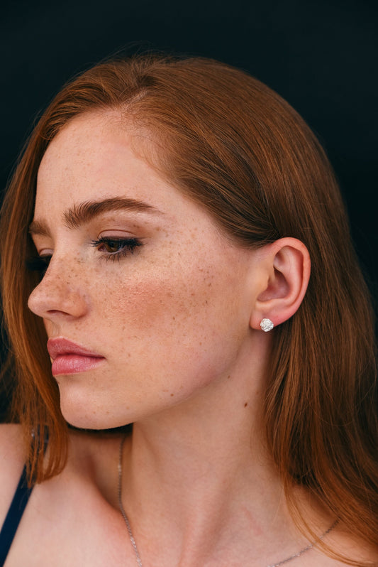Artisanal sculptural silver stud earrings worn by model.