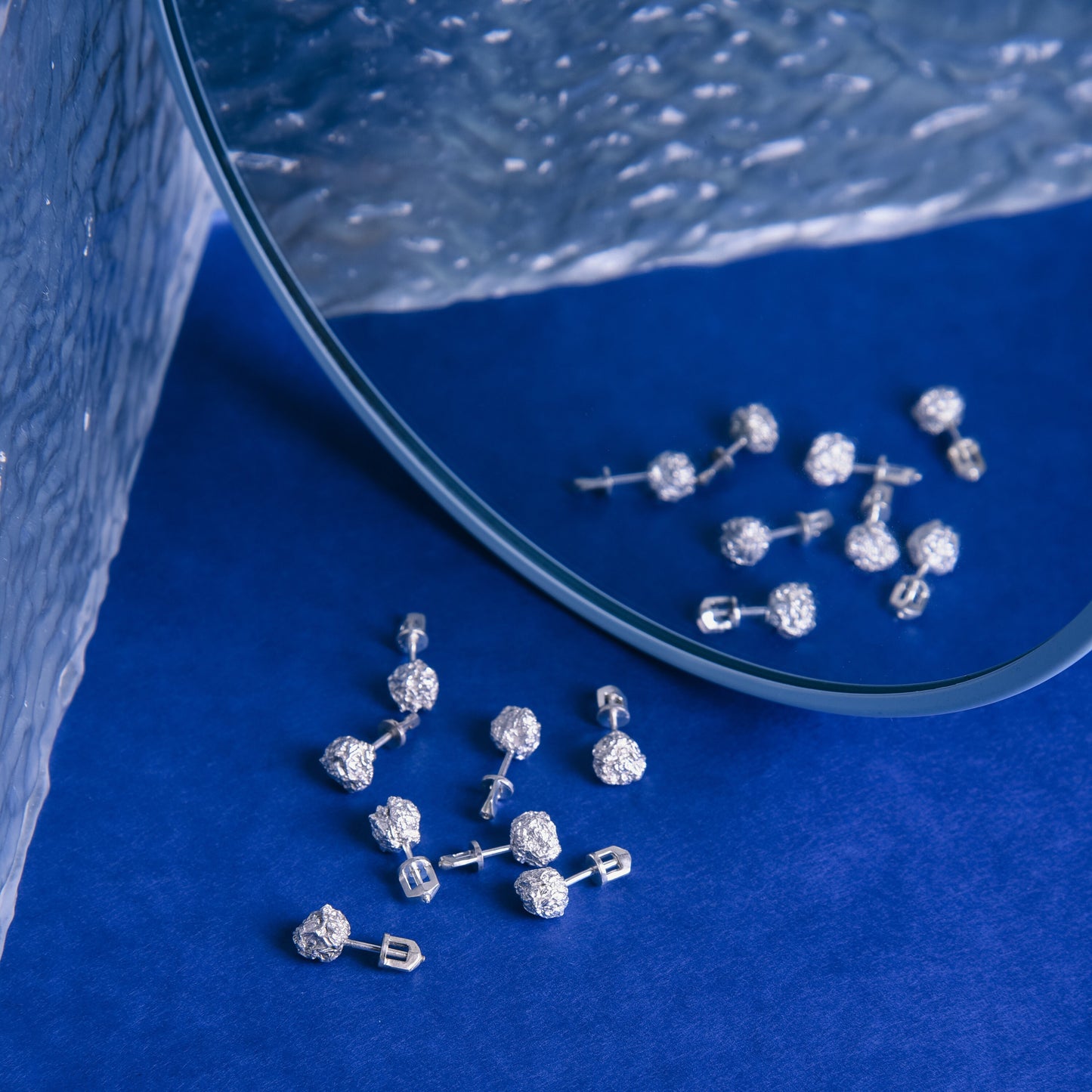 Minimalist silver studs displayed on blue background