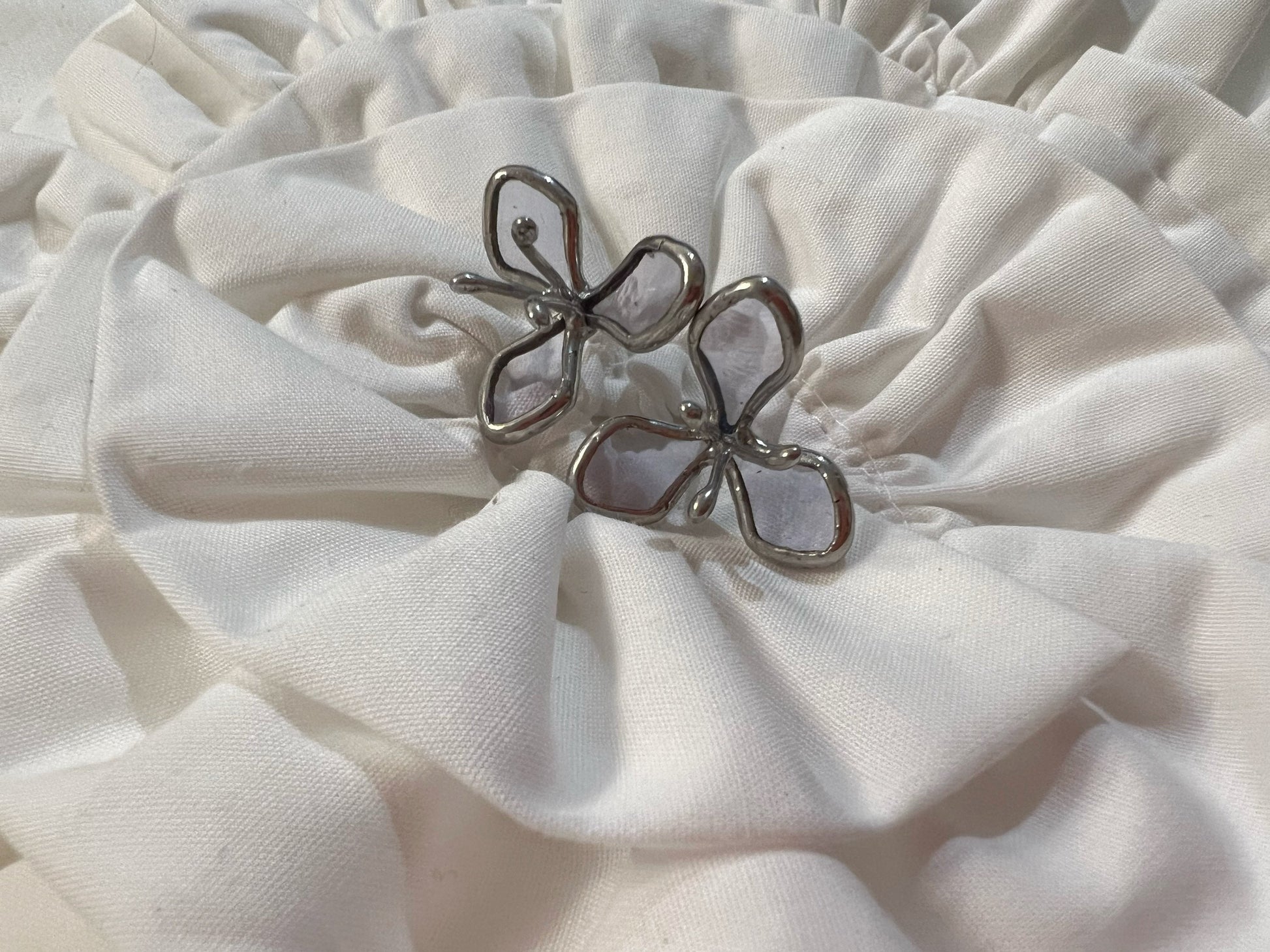 Light purple stained glass flower earrings on white cloth