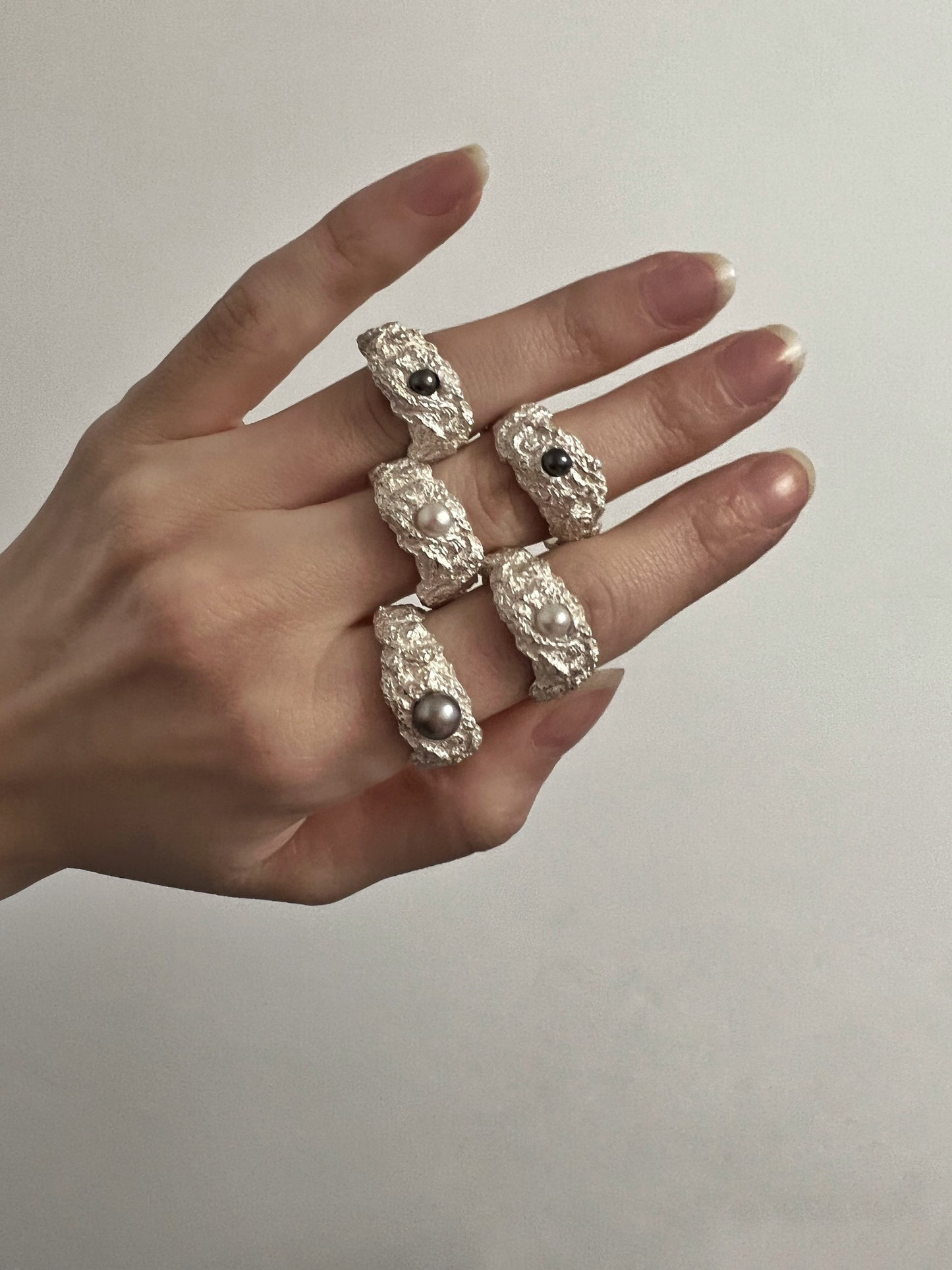 Multiple textured silver pearl rings shown on hand, unique designs