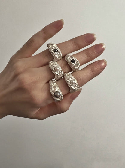 Close-up of textured silver pearl ring, minimalist background