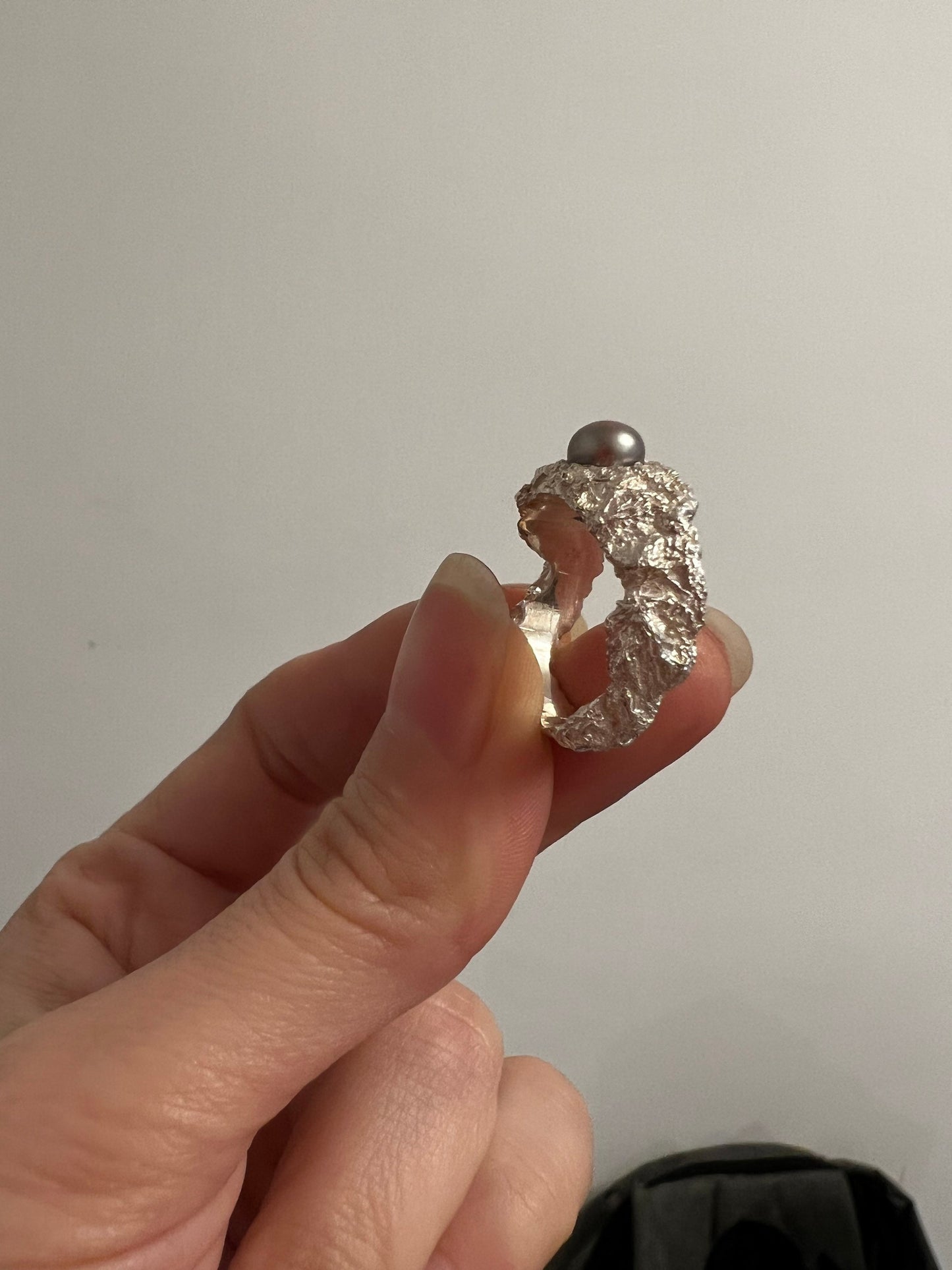 Handmade silver ring with pearl close-up, organic metal texture