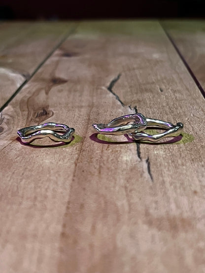 Three silver wavy rings on a wooden surface – molten wave rings set.