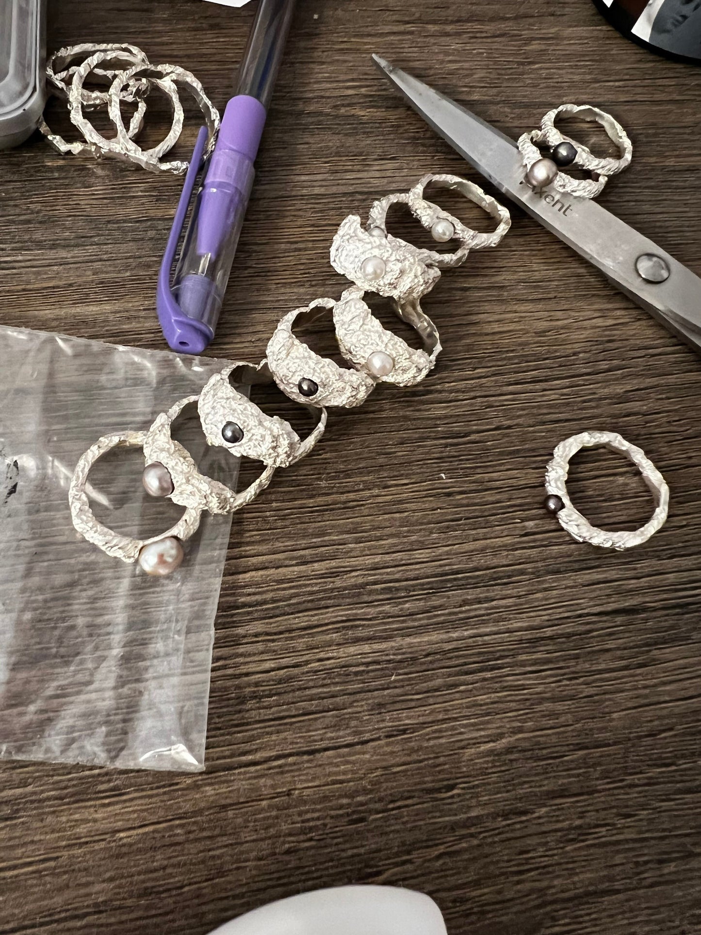 Multiple handmade silver dome rings with pearls on work table