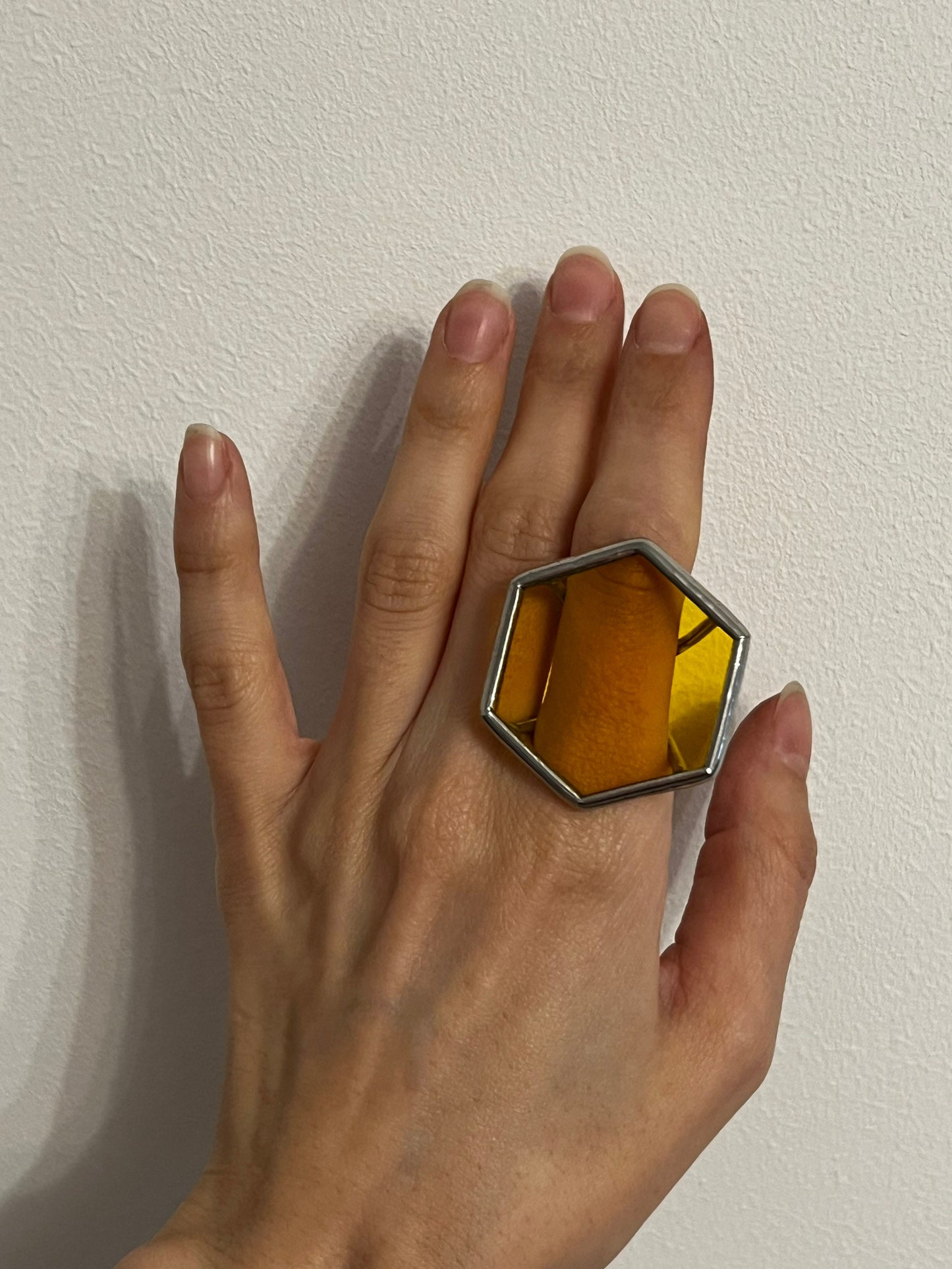 A large stained glass ring in the shape of a hexagon, the color of transparent yellow glass - an accent decoration in a geometric style.