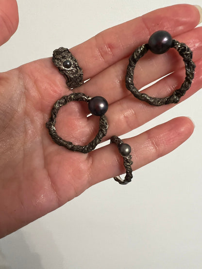 Set of oxidised silver rings with black pearls held in hand, artisan jewelry collection
