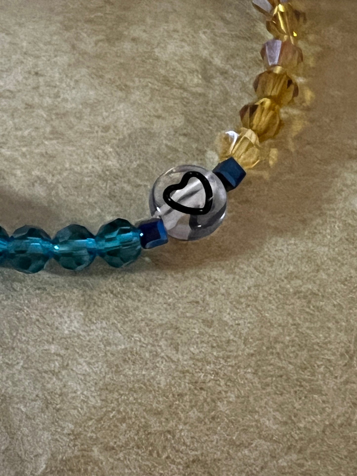Close-up of heart bead on blue yellow bracelet