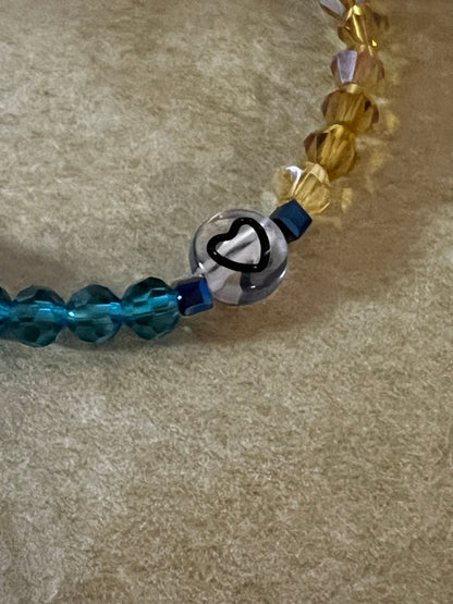 Close-up of heart bead on blue yellow bracelet