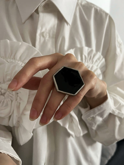 A large hexagonal ring with deep black glass and silver frame in the Tiffany technique.