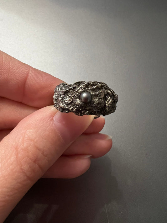 Close-up Hand with oxidized silver ring with black pearl, modern handmade jewelry.