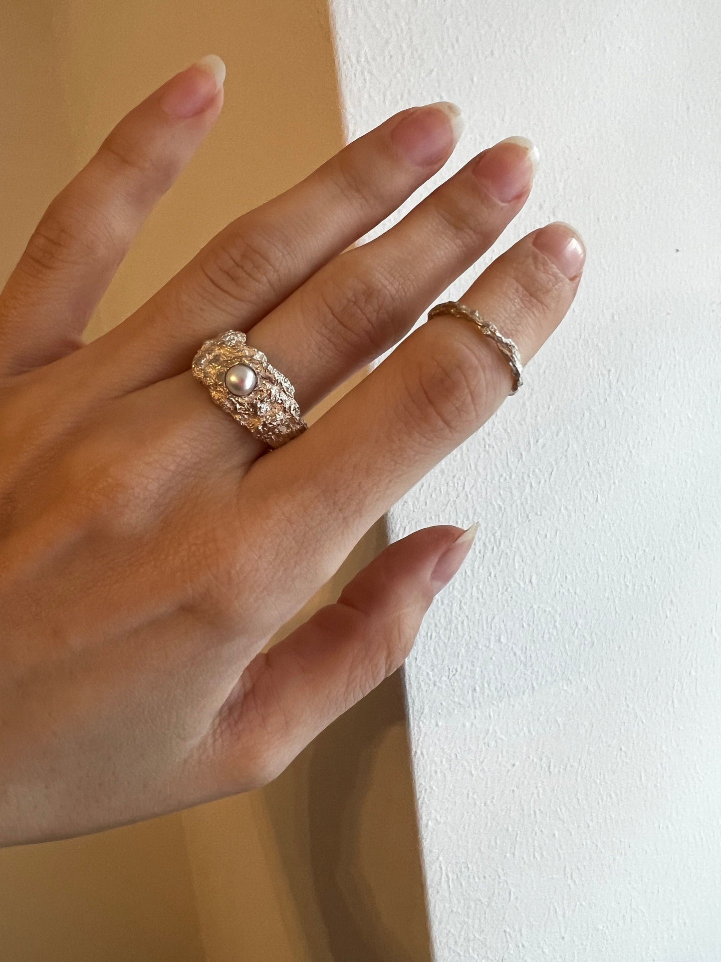 Sculptural silver ring with pearl worn on finger, modern art style