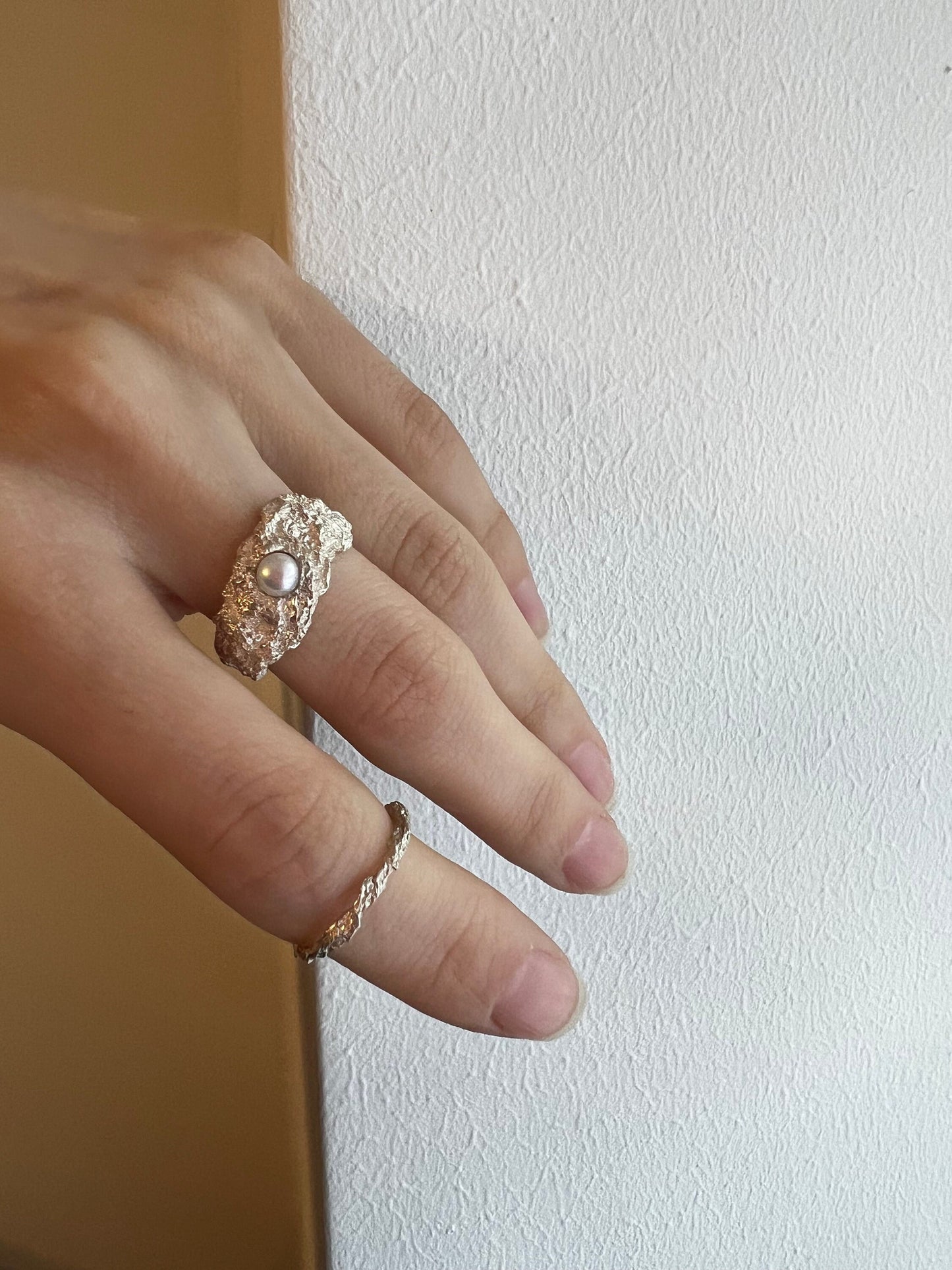Model holding handmade oxidized ring with pearl, artistic fashion tone