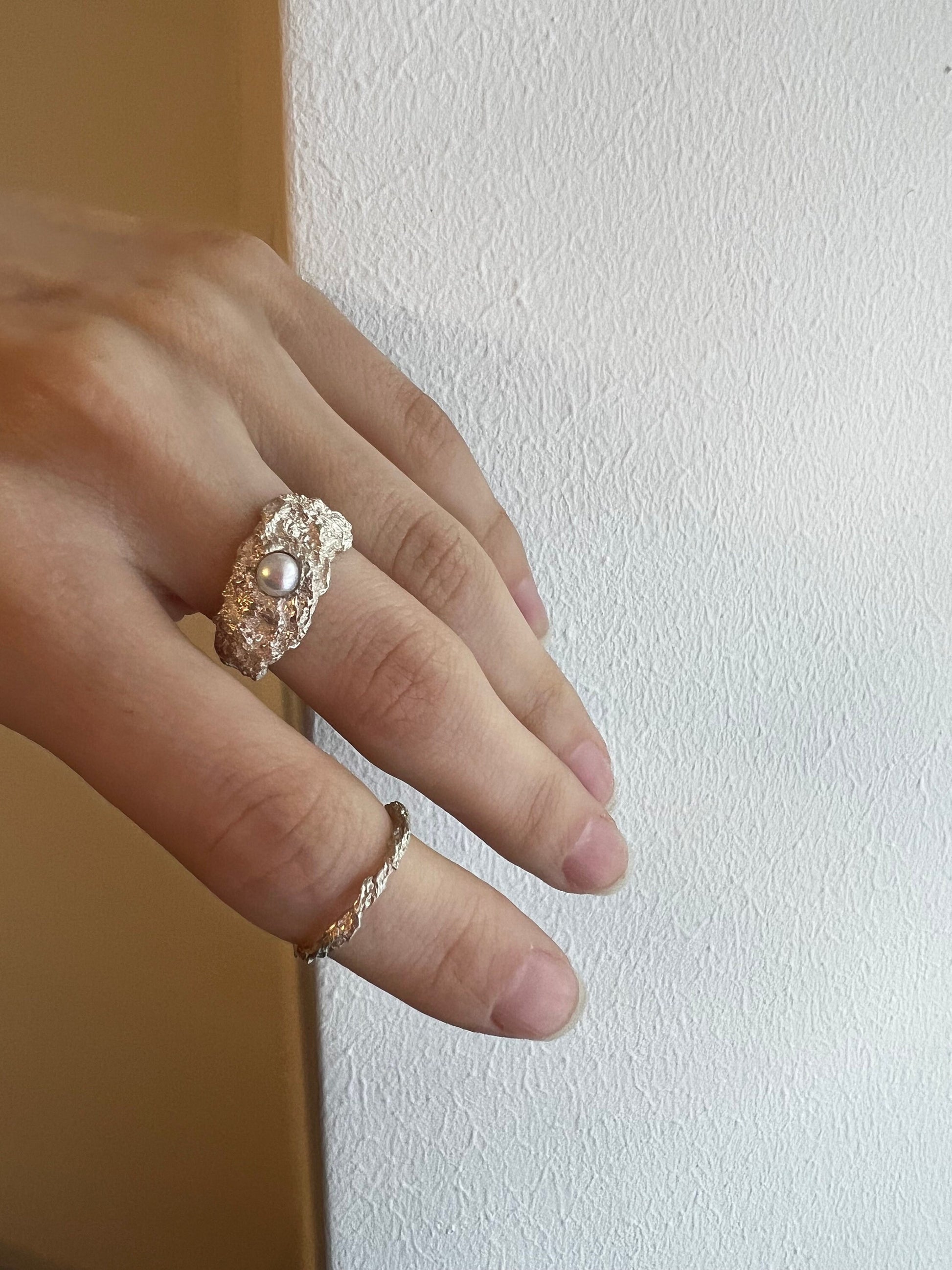 Model holding handmade oxidized ring with pearl, artistic fashion tone