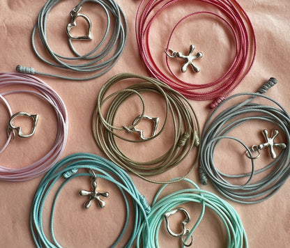 Collection of silver heart and flower charms on colorful nylon cords — modern gift idea